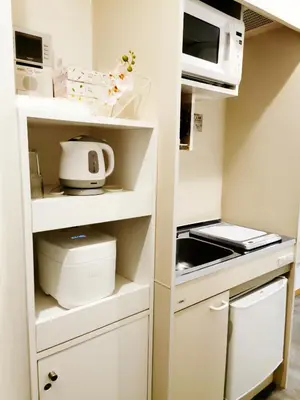 a small kitchen with white cabinets and a microwave at Fukuda House Shinjuku in Tokyo