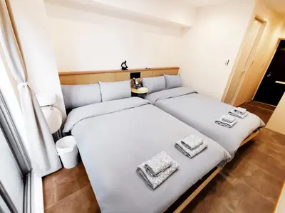 two beds in a small room with white sheets at Fukuda House Shinjuku in Tokyo