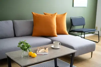 a grey couch with orange pillows and a table at mt \u4e2d\u91ce\u30d3\u30eb in Tokyo