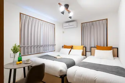 two beds in a small room with a table and a tableablish at mt \u4e2d\u91ce\u30d3\u30eb in Tokyo