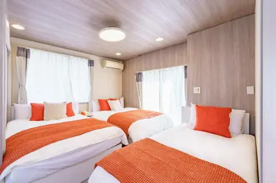 two beds in a room with windows at Enjoy Meguro House in Tokyo