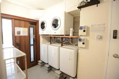 a laundry room with four washer and dryers at SleepTokyo in Tokyo