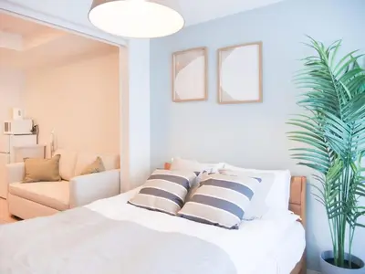 a bedroom with a bed with striped pillows and a couch at Triphome Sugamo Otsuka 2025 New 7 mins 2 stations in Tokyo