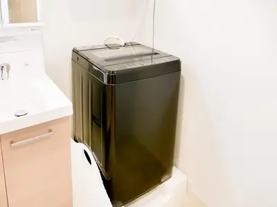 a black refrigerator in a bathroom next to a sink at Triphome Sugamo Minami-Otsuka Studio in Tokyo