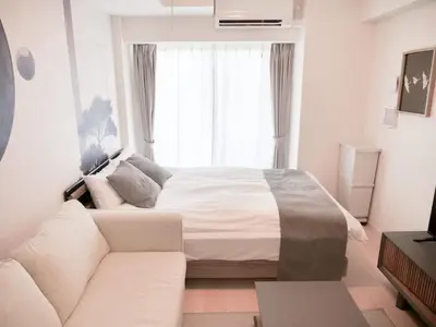 a white bedroom with a bed and a couch at Triphome Sugamo Minami-Otsuka Studio in Tokyo