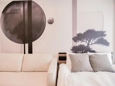 a living room with a couch and a tree on the wall at Triphome Sugamo Minami-Otsuka Studio in Tokyo