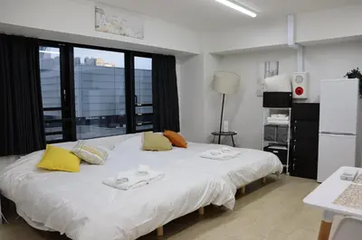 a bedroom with a large white bed with yellow pillows at \u30d5\u30a7\u30a4\u30b9\u864e\u30ce\u95808\u968e in Tokyo