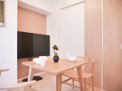 a dining room with a wooden table and a tv at Triphome Otsuka Sugamo in Tokyo
