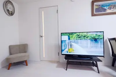 a flat screen tv sitting in a living room with a chair at Taito City Negishi 2Ldk-TT0323 in Tokyo