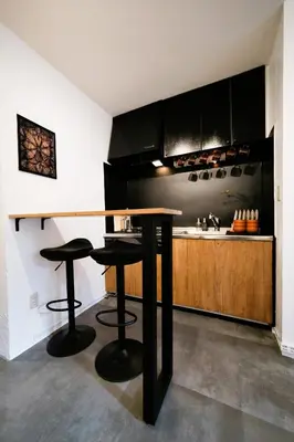 a kitchen with black cabinets and a counter with stools at Eden House - Vacation STAY 19890 in Tokyo