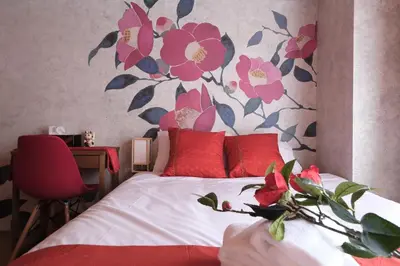 a bedroom with a bed with red pillows and a flower mural at Shinjuku Camellia Nest in Tokyo