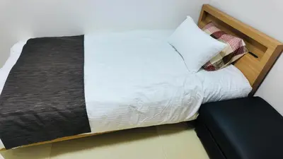 a bed with white sheets and pillows in a room at Tateishi House201 in Tokyo