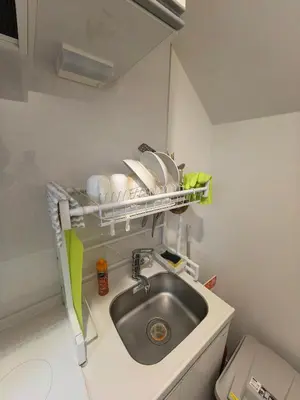 a kitchen sink with dishes on a shelf above it at Tateishi House201 in Tokyo