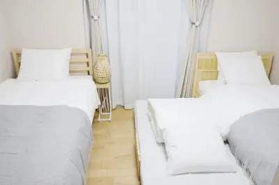 two beds in a room with white sheets at Dori Dori House Shinjuku1 in Tokyo