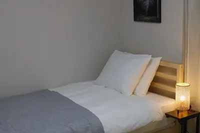 a bed with white sheets and pillows in a room at Dori Dori House Shinjuku1 in Tokyo