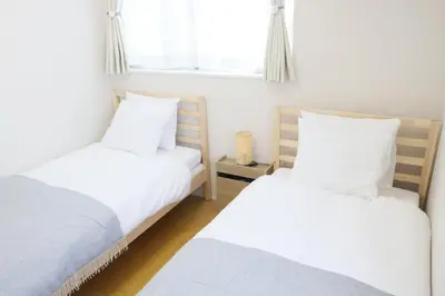 two twin beds in a room with a window at Dori Dori House Shinjuku1 in Tokyo