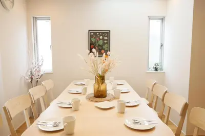 a table with white chairs and a vase of flowers on it at Dori Dori House Shinjuku1 in Tokyo