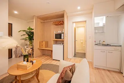 a living room with a table and a kitchen at Mi-HOTEL SUGAMO in Tokyo