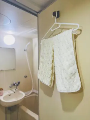 a white towel hanging on a wall next to a sink at Shinjuku\u65b0\u5bbf1min in Tokyo