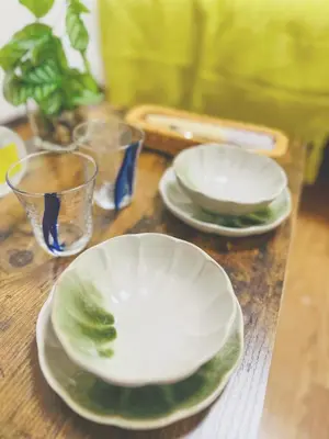 two plates and glasses sitting on a wooden table at Shinjuku\u65b0\u5bbf1min in Tokyo