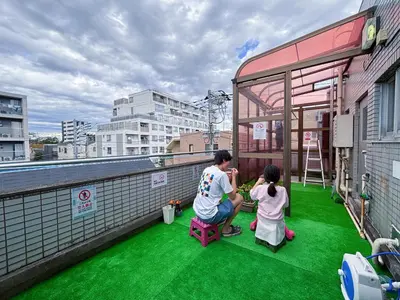 a man and two girls on a balcony with green grass at Direct to Shinjuku 15 mins 3rooms Up to 9 Guests in Tokyo