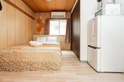 a small bedroom with a bed and a refrigerator at Luna Nest Ikebukuro in Tokyo