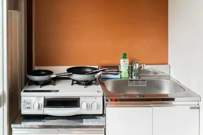 a kitchen with two pans on a stove and a sink at Luna Nest Ikebukuro in Tokyo