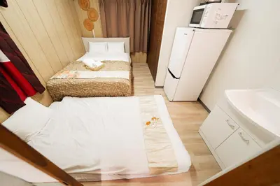 a small room with two beds and a refrigerator at Luna Nest Ikebukuro in Tokyo