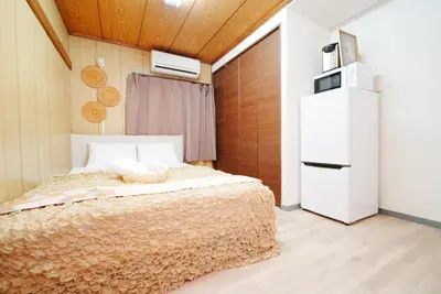 a bedroom with a bed and a refrigerator at Luna Nest Ikebukuro in Tokyo