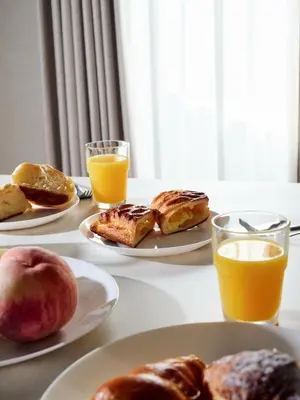 a table with plates of pastries and glasses of orange juice at \u3068\u307e\u308a\u30fc\u3068Stay \u7acb\u4f1a\u5ddd Tomareat Stay Tachiaigawa in Tokyo