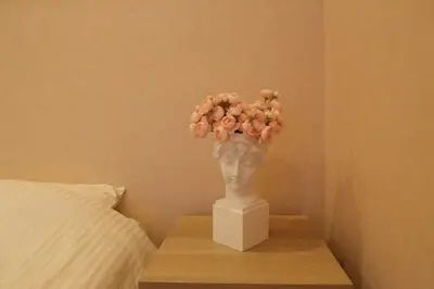 a vase of flowers on a table next to a bed at Maple & Ginkgo Views Autumn Stay Up To 9 N201 in Tokyo