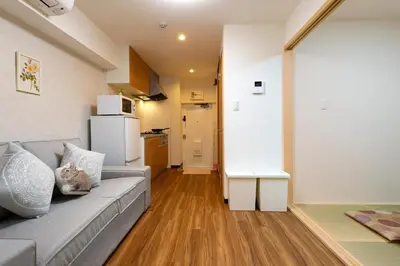 a living room with a gray couch and a kitchen at Maple & Ginkgo ViewsAutumn Stay Near Ikebukuro N102 in Tokyo