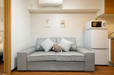 a couch in a living room with a microwave at Maple & Ginkgo ViewsAutumn Stay Near Ikebukuro N102 in Tokyo