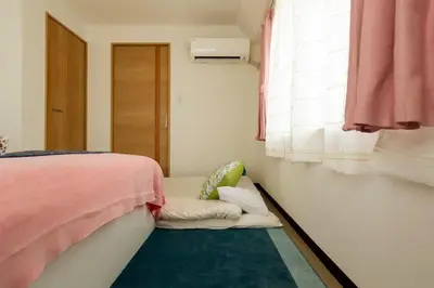 a bedroom with a bed and a chair next to a window at Maple & Ginkgo ViewsAutumn Stay Near Ikebukuro N303 in Tokyo