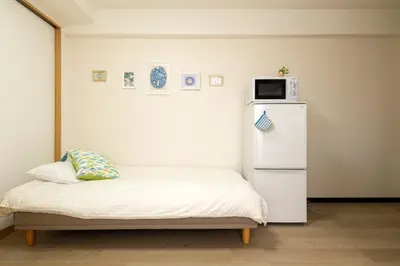 a room with a small bed with a small refrigerator at Maple & Ginkgo ViewsAutumn Stay Near Ikebukuro N303 in Tokyo