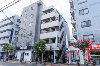 a tall white building on a city street at Cruise Inn Takenotsuka in Tokyo