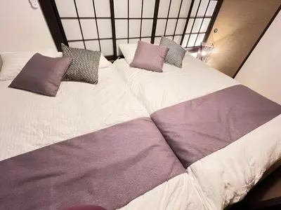 two beds with purple and white sheets and pillows at Tiare Home MOTOHASUNUMA in Tokyo