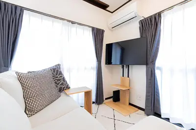 a living room with a couch and a flat screen tv at Tiare Home MOTOHASUNUMA in Tokyo