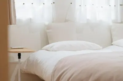 a bed with white sheets and a night stand next to a window at K06 Quiet 2LDK house on JR Yamanote Line Komagome Station in Tokyo
