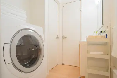 a white washing machine in a white laundry room at K06 Quiet 2LDK house on JR Yamanote Line Komagome Station in Tokyo
