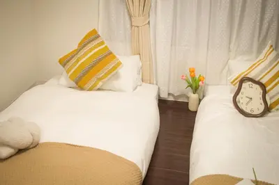 a bedroom with two beds with a clock and flowers at Ikebukuro mansion,4-6people,two bedrooms,subway 5mins in Tokyo