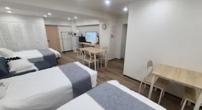 a room with two beds and a table and a desk at Okubo, 20 seconds walk from JR Okubo Station in Tokyo