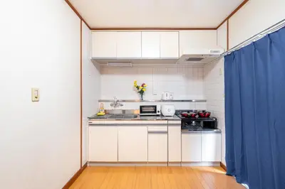 a kitchen with white cabinets and a blue curtain at Cozy Apartment, 2min to Station , Direct to Skytree, Asakusa & Ueno & Narita ,駅2分,スカイツリー浅草上野成田空港直結,エレベーター,スーパー2分,コンビニ1分 in Tokyo