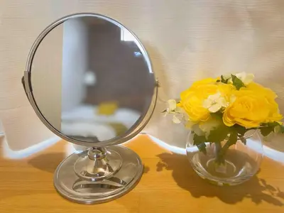 a mirror and a vase with yellow flowers on a table at Pine House 6 minutes by train to Ikebukuro 11 minutes to Shinjuku Convenient access to Ueno by train in Tokyo
