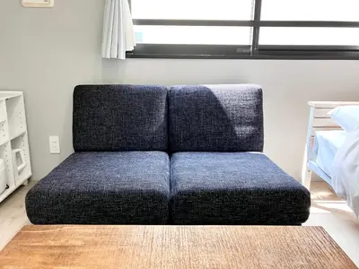 a blue couch sitting in a room next to a bed at KOU Jiyugaoka 202 in Tokyo