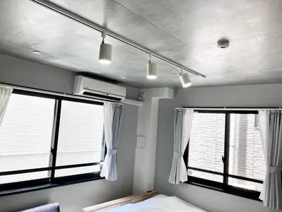 a bedroom with two windows with white curtains and a bed at KOU Jiyugaoka 202 in Tokyo