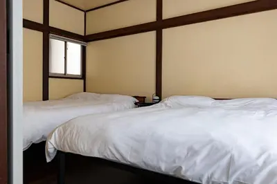 two beds in a room with white sheets at KOU Ikebukuro in Tokyo