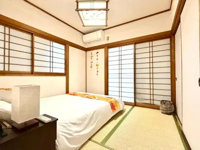 a bedroom with a bed and windows and a television at Ninja Tokyo Hideaway Higashi-Shinkoiwa in Tokyo