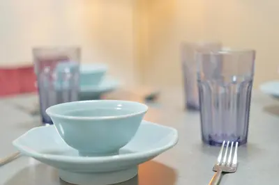 a table with a bowl and a fork and glasses at The underz suite residence Ikebukuro by Tranova in Tokyo