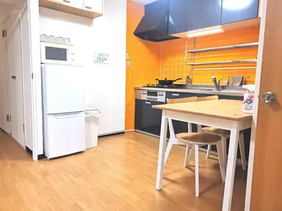 a kitchen with a white refrigerator and a table with chairs at A Stay in Shinjuku in Tokyo
